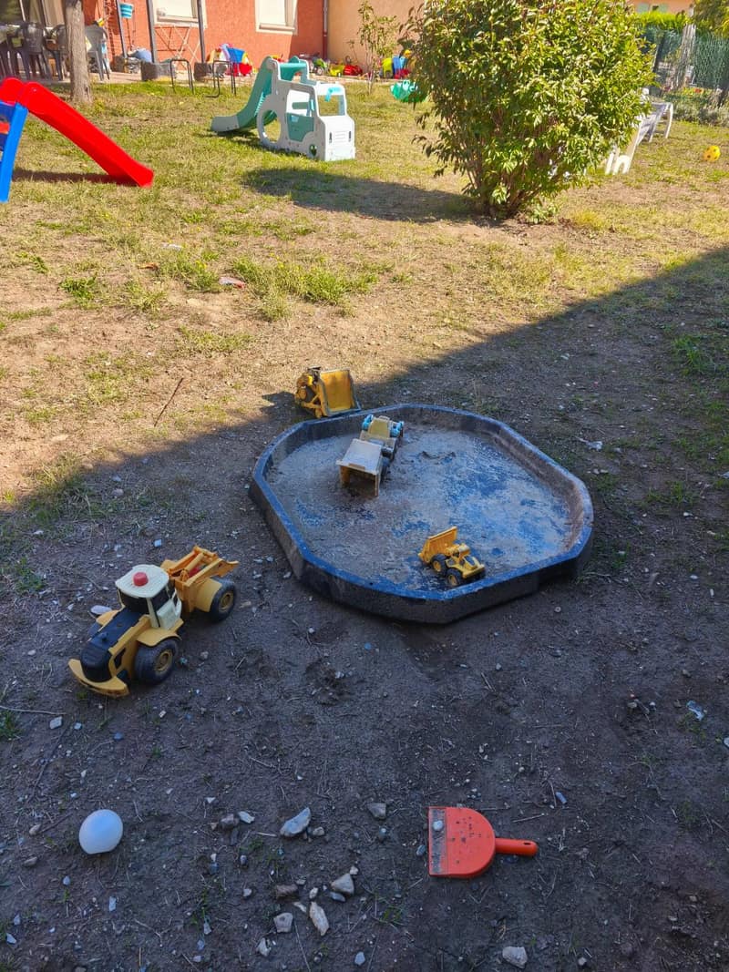 Le jardin d'accueil à Espinasses : toboggans, bac à sable avec tracteurs et pelouse pour jouer dehors